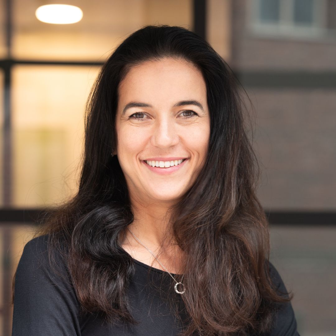 Porträtfoto einer Mitarbeiterin der Zahnarztpraxis Dr. Carolin Habermeier, freundlich lächelnd vor modernem Hintergrund.